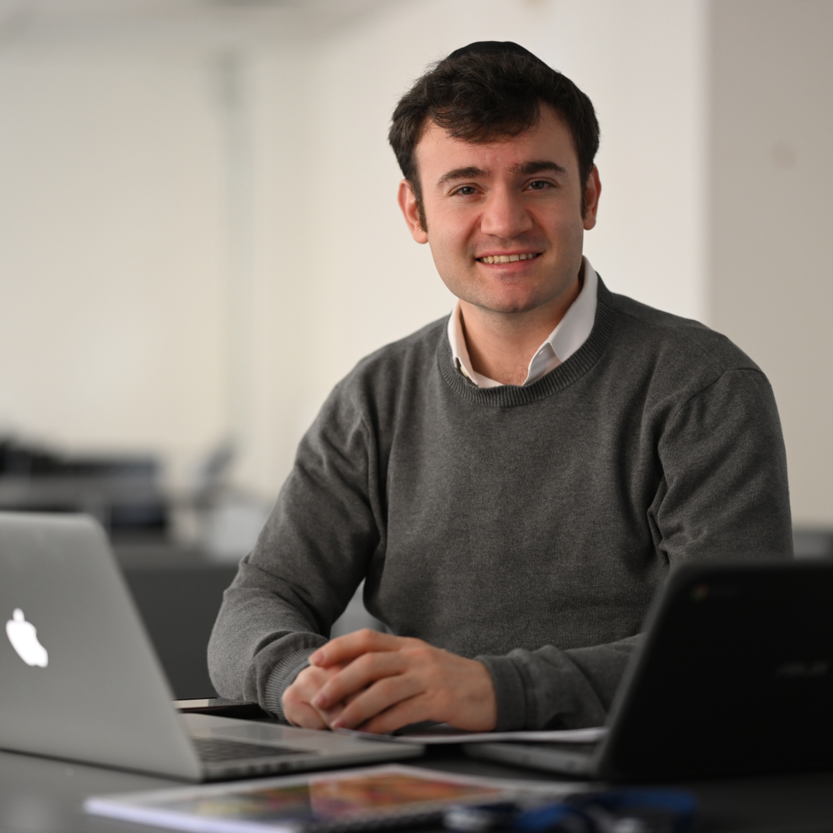 Male professor smiling at desk with computer